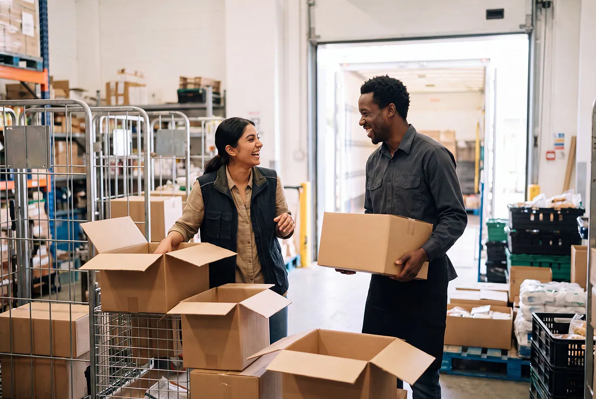 A store manager and a merchandiser unpacking a delivery in a bright stockroom